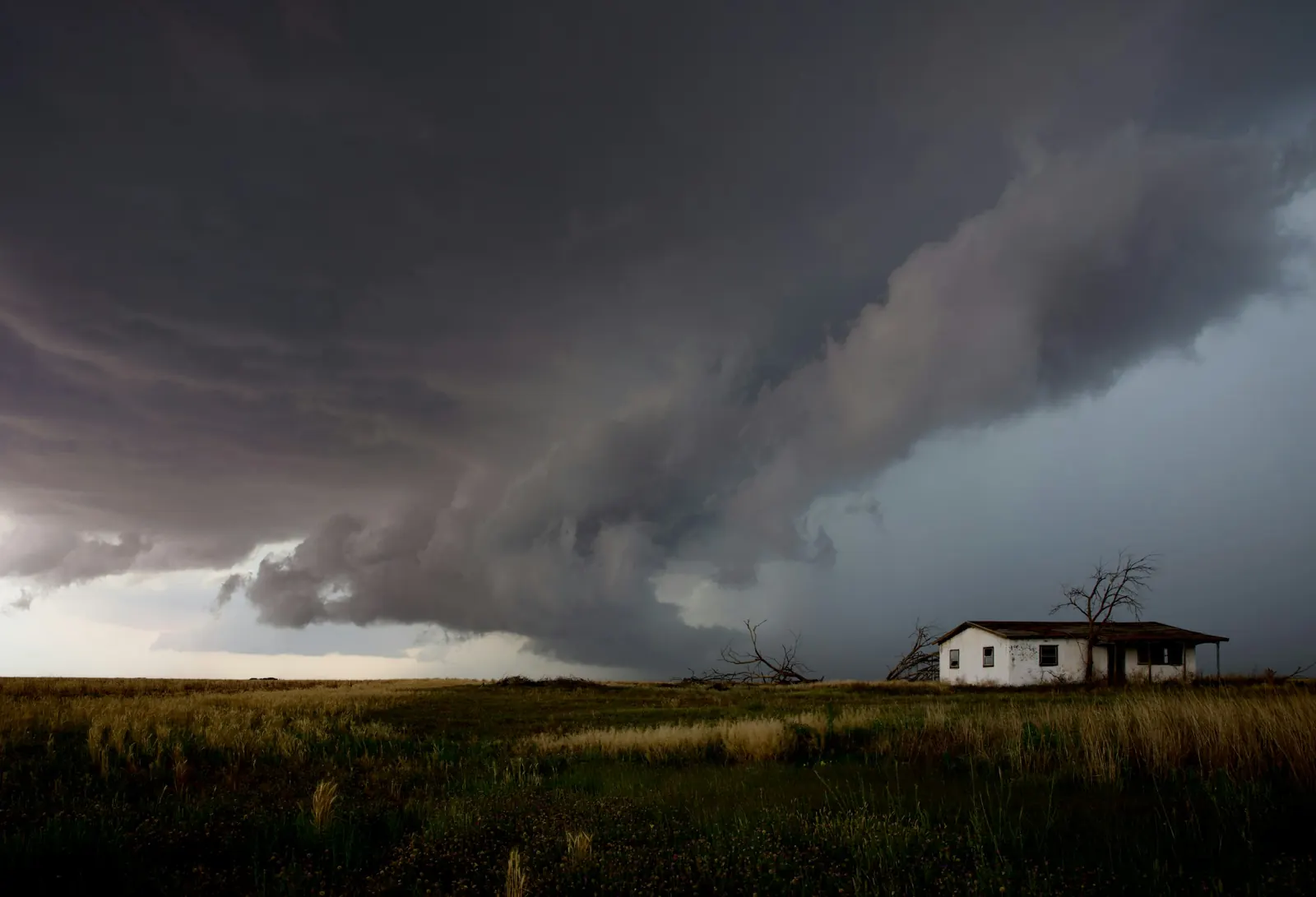 A storm cell building over a lone house on the plains